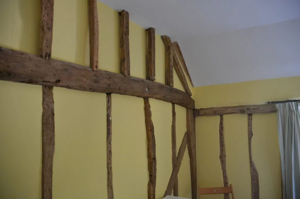 A room corner with exposed wooden beams on yellow walls