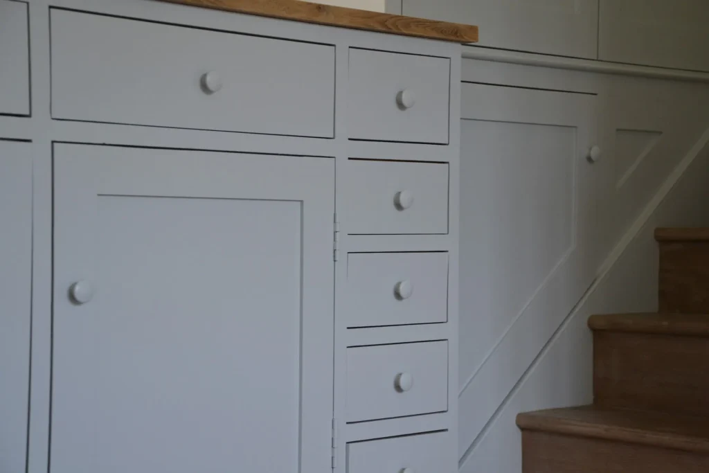 White built-in cabinet with multiple drawers adjacent to wooden stairs