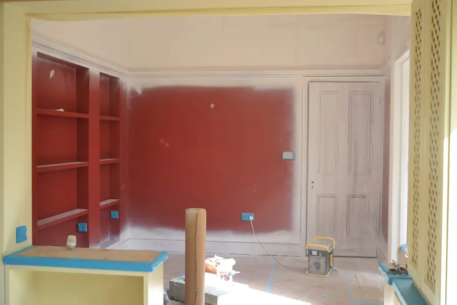 Sitting room mid-redecoration — shelving masked, floors sheeted
