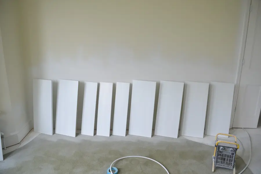 Freshly painted shelf panels drying in a line