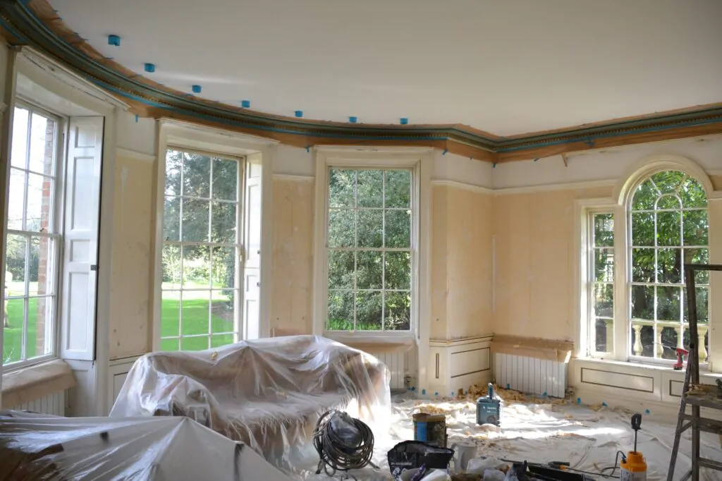 A room under renovation with furniture covered with plastic sheets