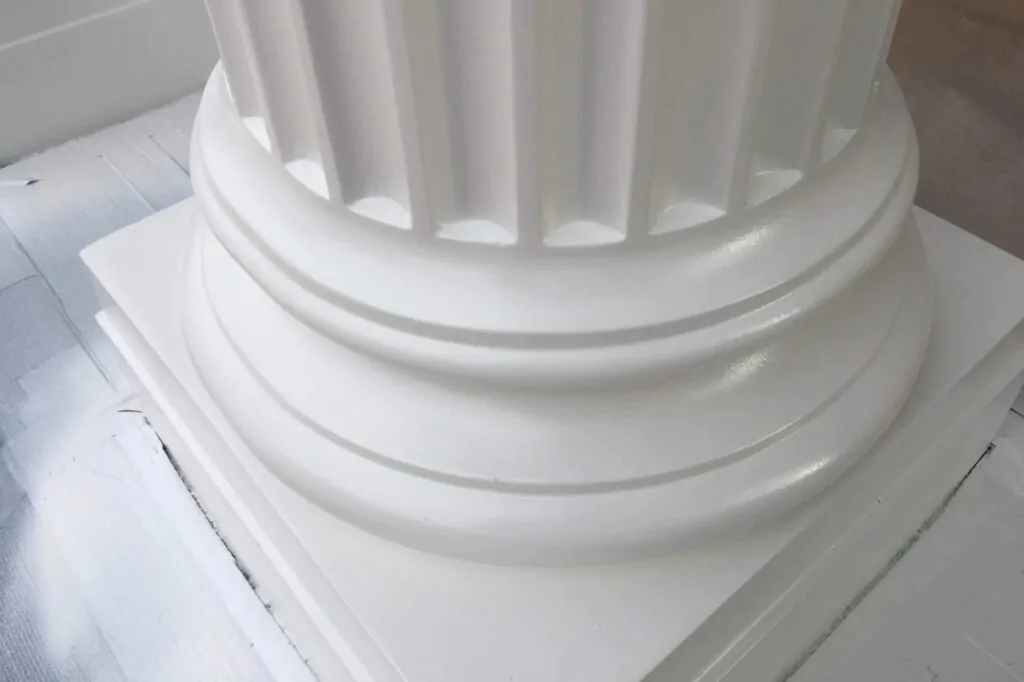Base of a fluted white column on a painted light-coloured floor