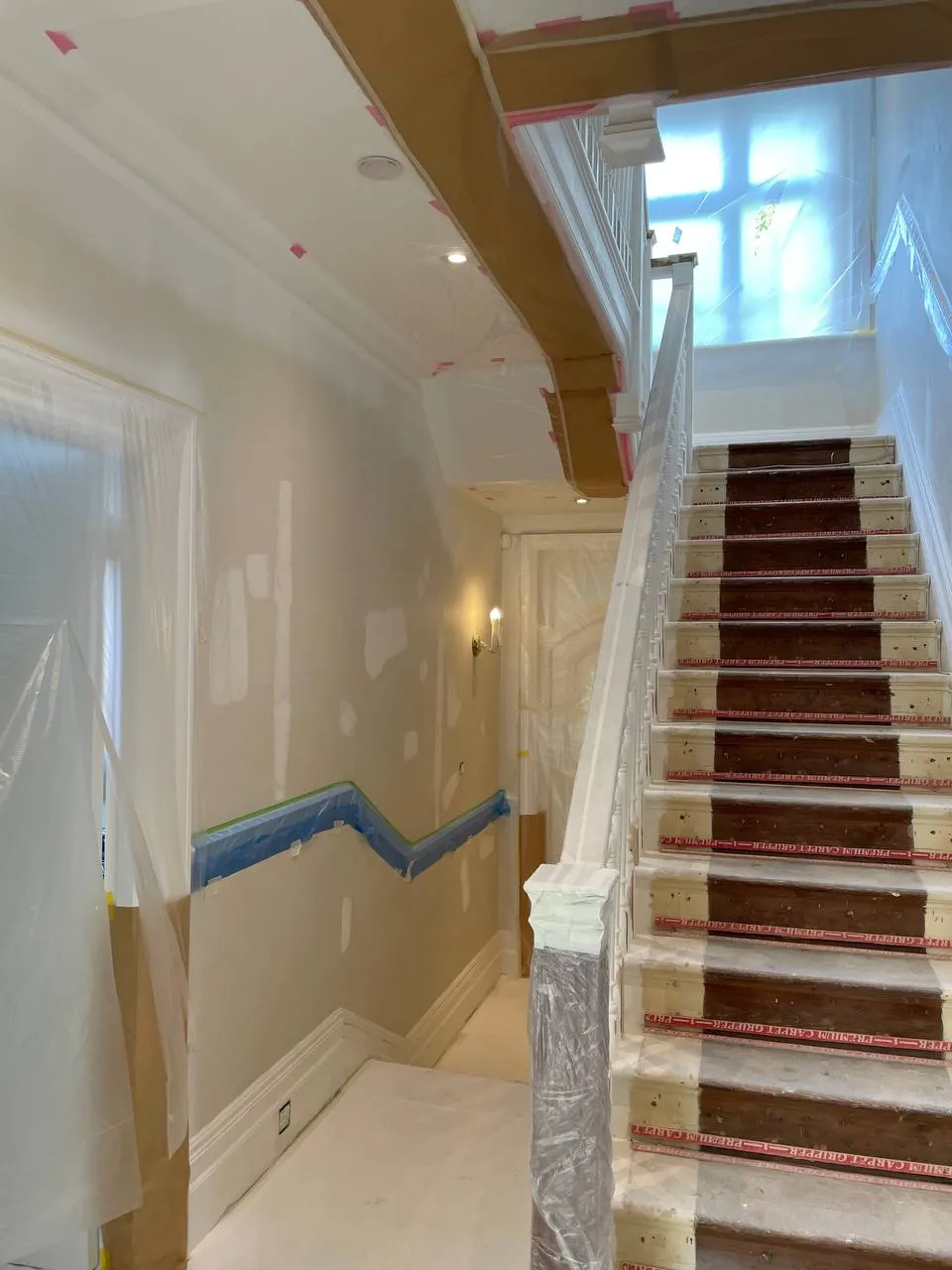 Grand period staircase with a red stair runner and freshly painted balustrade