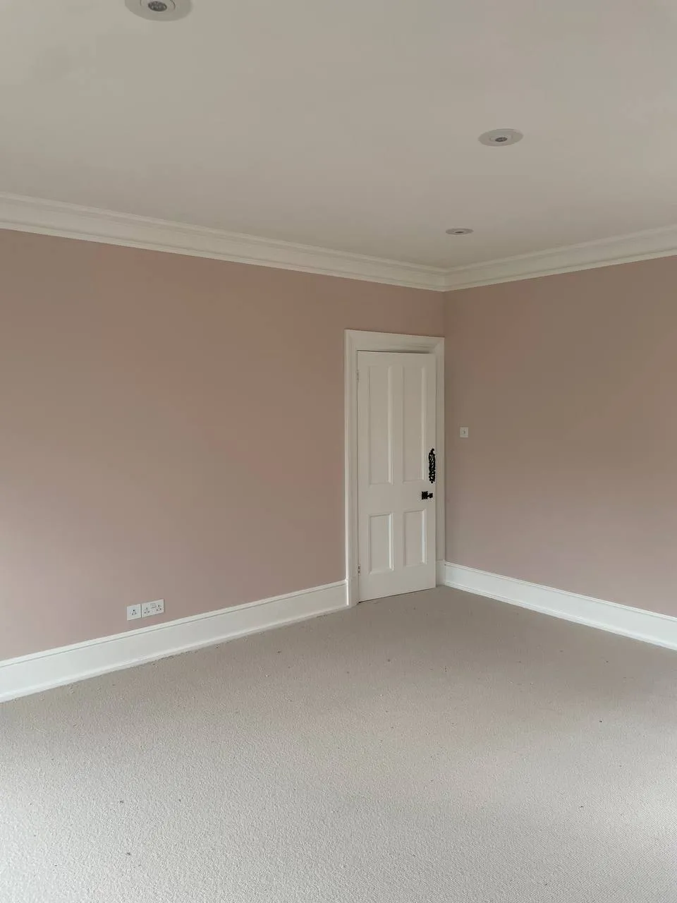 Period bedroom decorated in soft pink with a panelled door repainted