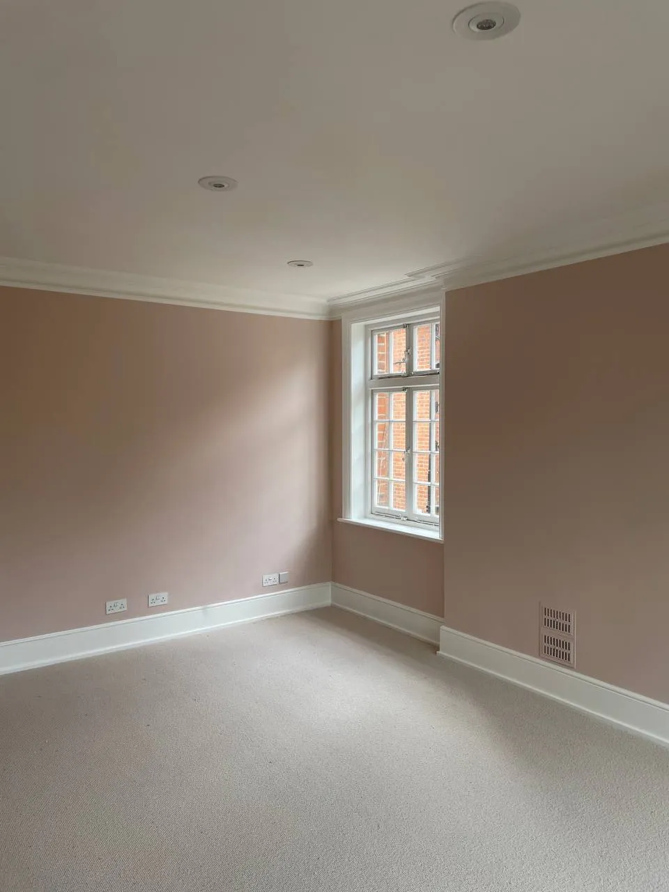 Dusky-pink bedroom with a crisp white window and skirting