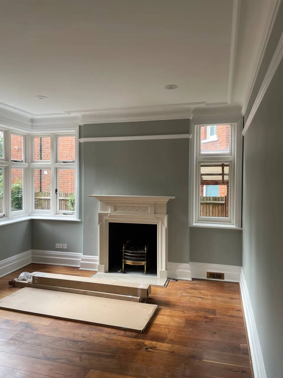 Period reception room decorated in sage green with an original fireplace and cornicing