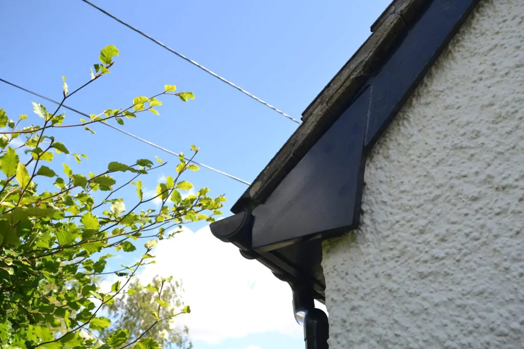 Close-up of a house roofline with black guttering against a blue sky