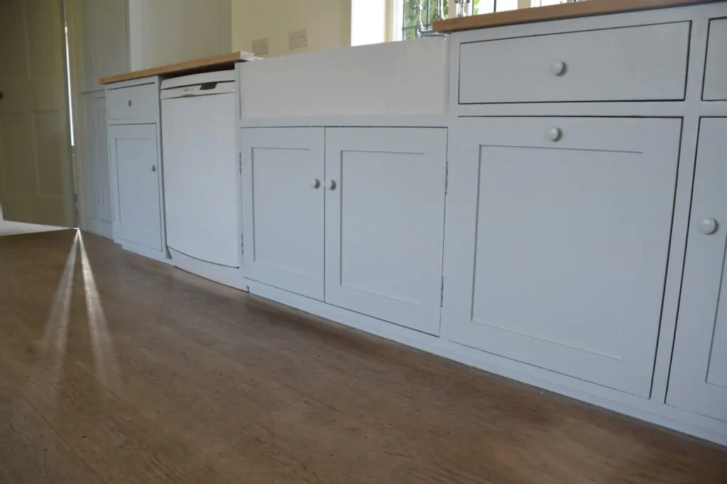 White kitchen cabinets with simple knobs and a wooden countertop