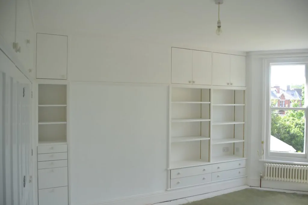 Empty room with white built-in shelves and large window